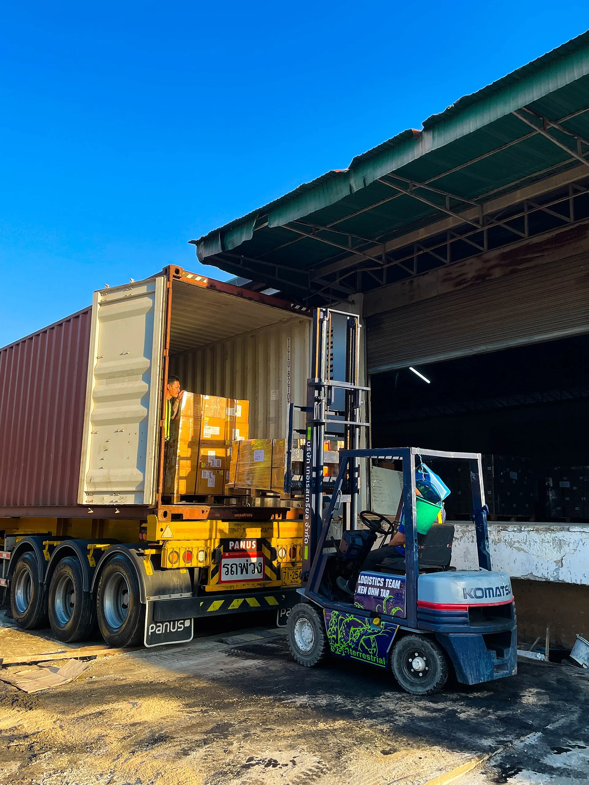 Forklift loading cargo into a shipping container at a warehouse